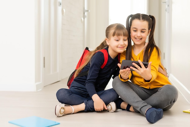 gente, niños, tecnología, amigos y concepto de amistad - niñas felices con smartphones tirados en el suelo en casa.