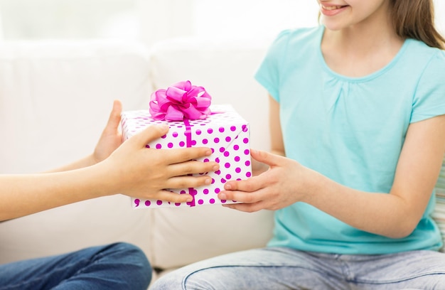 gente, niños, vacaciones, amigos y concepto de amistad - cerca de niñas felices con regalo de cumpleaños sentadas en un sofá en casa