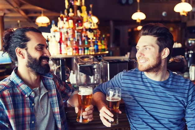 gente, ocio, amistad, comunicación y concepto de despedida de soltero - amigos varones felices bebiendo cerveza y hablando en el bar o pub