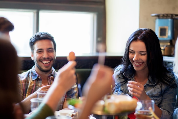 Foto gente, ocio, amistad y concepto de comunicación - amigos felices bebiendo cerveza y comiendo bocadillos en el bar o pub