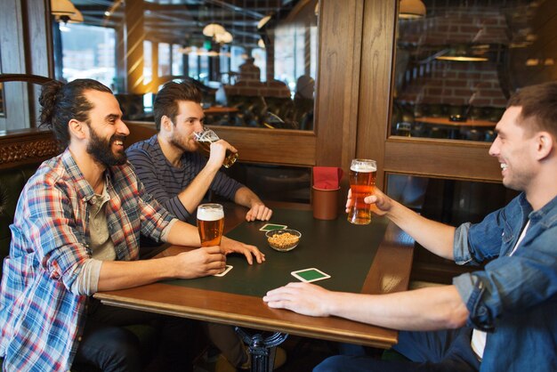 gente, ocio, amistad y concepto de despedida de soltero - amigos varones felices bebiendo cerveza en el bar o pub