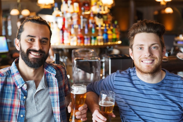 gente, ocio, amistad y concepto de despedida de soltero - amigos varones felices bebiendo cerveza y hablando en el bar o pub