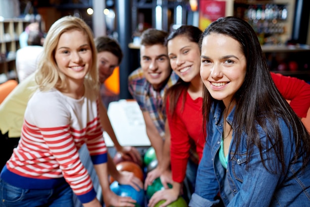 Foto gente, ocio, deporte, amistad y concepto de entretenimiento - amigos felices en el club de bolos