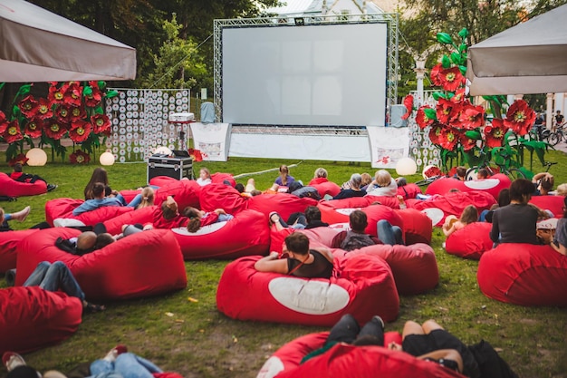 Gente en el parque público de la ciudad viendo películas en el cine al aire libre