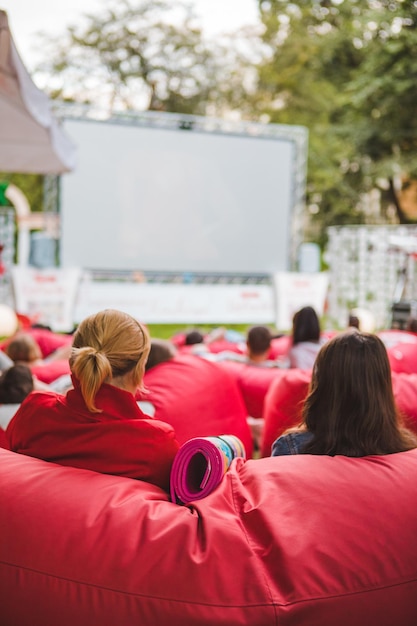 Gente en el parque público de la ciudad viendo películas en el cine al aire libre