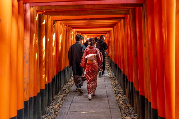 La gente pasa bajo el torii del templo de Fushimi inari