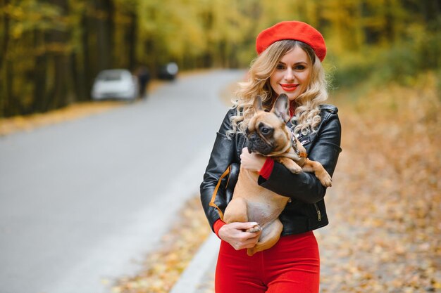 Gente y perros al aire libre Mujer hermosa y feliz disfrutando en el parque de otoño caminando con su adorable bulldog francés