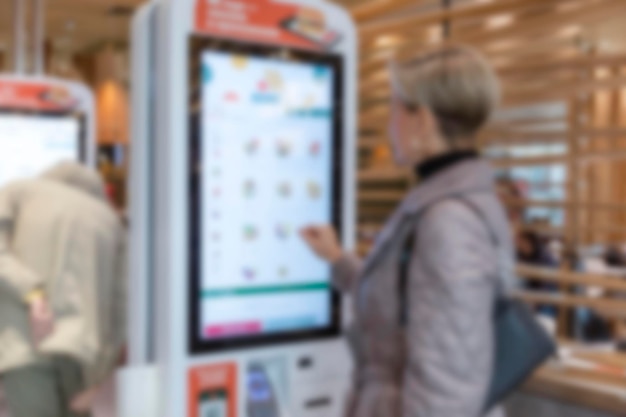 La gente pide comida rápida en un monitor en una cafetería Comida poco saludable y nutrición borrosa