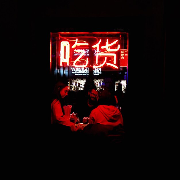 Foto gente de pie en un letrero iluminado por la noche