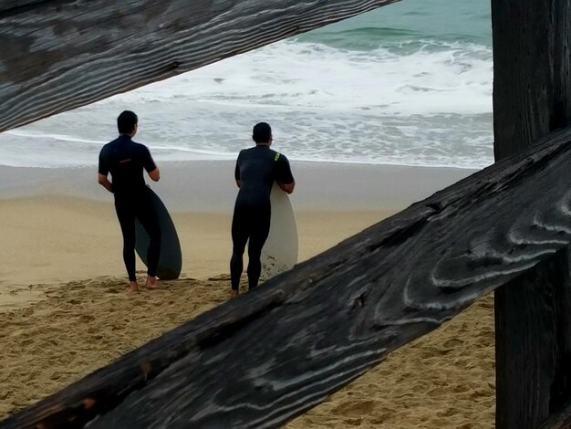 Foto gente de pie en la playa junto al mar contra el cielo