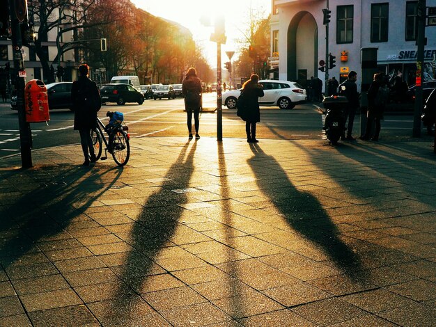 Foto gente de pie con la sombra en el sendero durante la puesta de sol en la ciudad