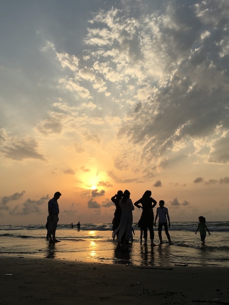 Gente en la playa del mar al atardecer divirtiéndose