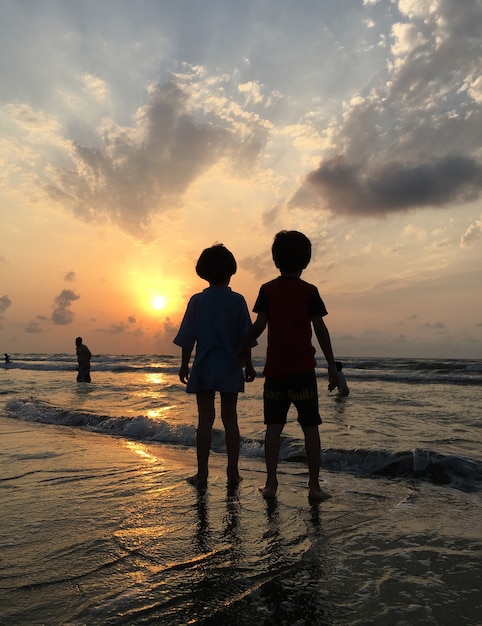 Gente en la playa del mar al atardecer divirtiéndose