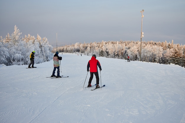 La gente practica snowboard y esquí, actividades invernales y deportes. Esquiar montaña abajo en una tabla de snowboard, emociones divertidas en los rostros de hombres y mujeres