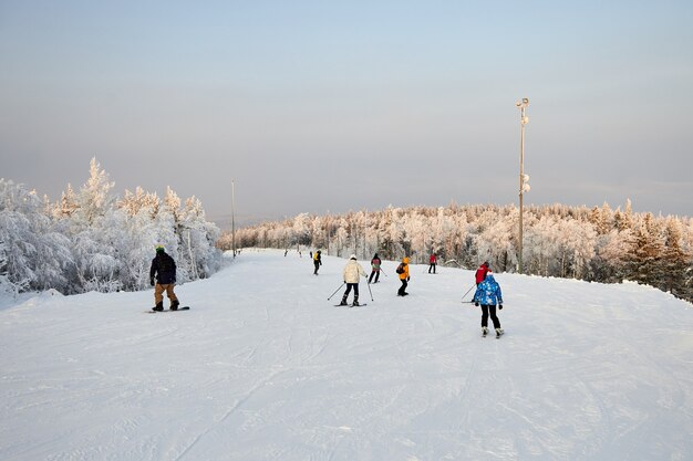 La gente practica snowboard y esquí, actividades invernales y deportes. Esquiar montaña abajo en una tabla de snowboard, emociones divertidas en los rostros de hombres y mujeres