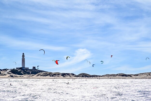 Gente practicando kitesurf en la playa de los caos de meca, faro de trafalgar, cadiz.