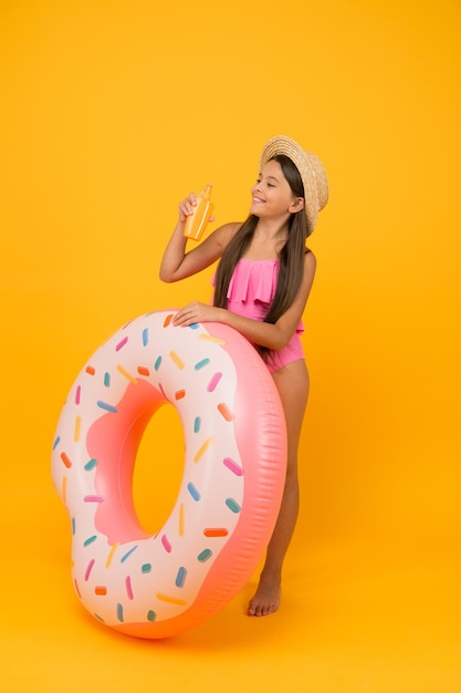 Gente protección de la piel infancia felicidad niño cuidado de la salud pequeña belleza niño feliz con anillo de goma actividad de vacaciones de verano niña alegre usar traje de baño y sombrero de paja diversión en la piscina y la playa