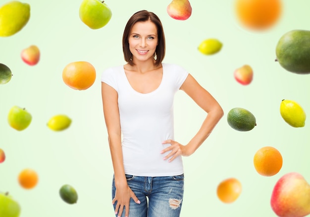 gente, publicidad, dieta, comida y concepto de alimentación saludable - mujer feliz con camiseta blanca en blanco sobre frutas de fondo verde