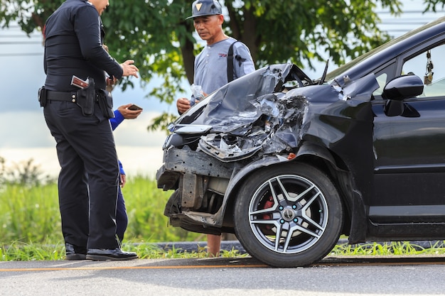 Gente que controla el frente del automóvil negro que se dañó por accidente