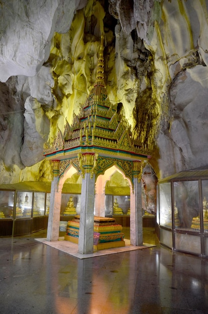 Gente que ruega con la estatua de Buda dentro de la cueva en Wat Tham Khao Yoi