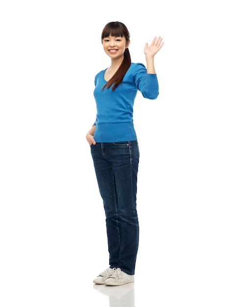 Foto gente, raza, etnia y concepto de gesto - feliz sonriente joven mujer asiática agitando la mano sobre blanco