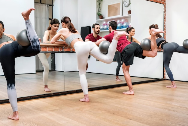 Gente realizando una extensión de cadera con bolas en la barra en el gimnasio