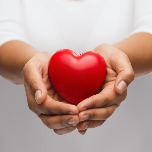 gente, relación y concepto de amor - primer plano de las manos ahuecadas de las mujeres que muestran el corazón rojo