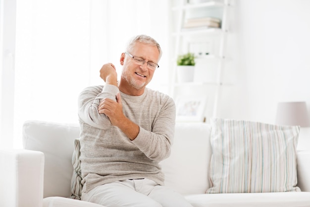 gente, salud y concepto de problema - anciano infeliz que sufre de dolor de codo en casa