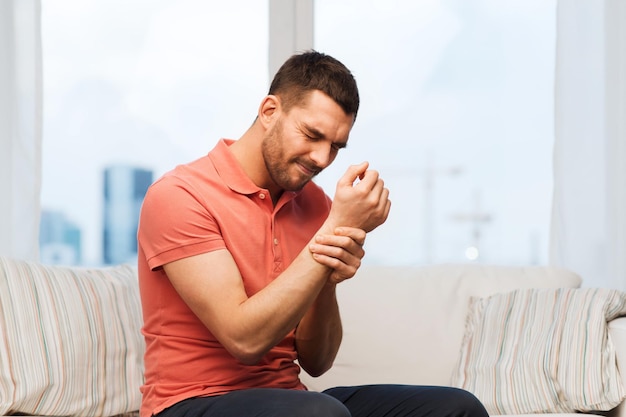 gente, salud y concepto de problema - hombre infeliz que sufre de dolor en la mano en casa