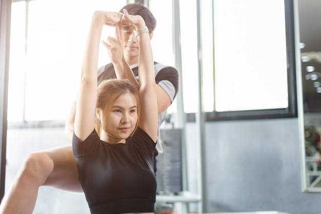 Gente sana, mujer joven asiática, ejercicio deportivo en gimnasio, club deportivo con instructores de entrenador personal, ayuda a apoyar