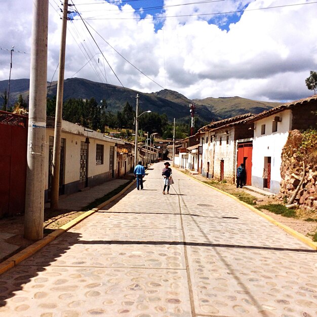 Foto la gente en el sendero en medio de las casas contra el cielo