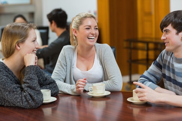 Gente sentada en la cafetería sonriendo