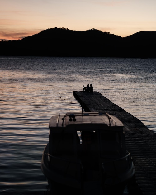 Gente sentada en un muelle en un lago al atardecer