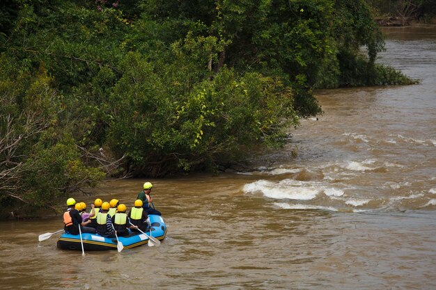 Foto gente sentada en el río contra los árboles