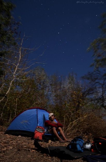 Foto la gente sentada en la tierra contra el cielo por la noche