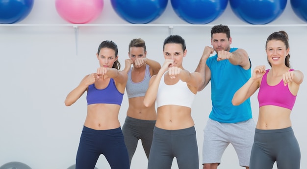 Gente sonriente haciendo ejercicio físico de poder en la clase de yoga