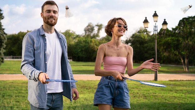 Gente sonriente jugando bádminton tiro medio