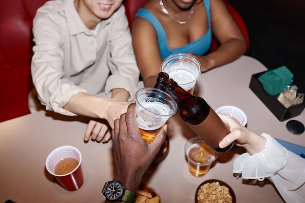 Gente sosteniendo botellas de cerveza sobre la mesa del comedor juntos