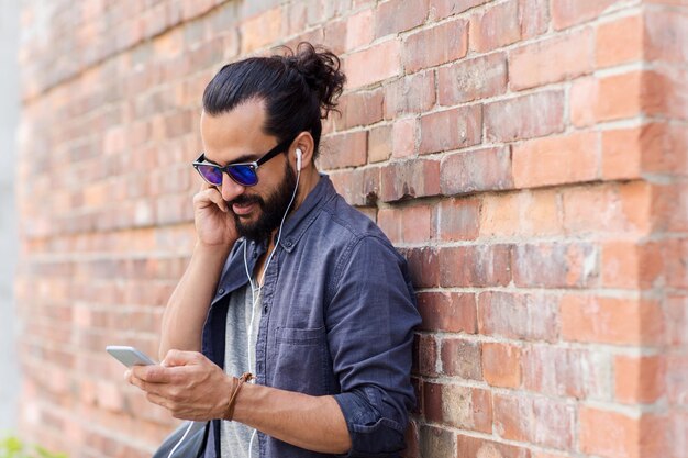 gente, tecnología, ocio y estilo de vida - hombre con auriculares y smartphone escuchando música en la calle de la ciudad