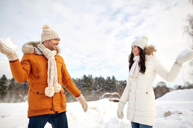 gente, temporada, amor y concepto de ocio - pareja feliz jugando bolas de nieve en invierno