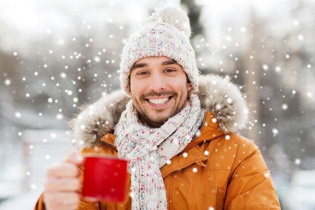 gente, temporada, bebidas y concepto de ocio - hombre feliz con taza de té al aire libre en invierno