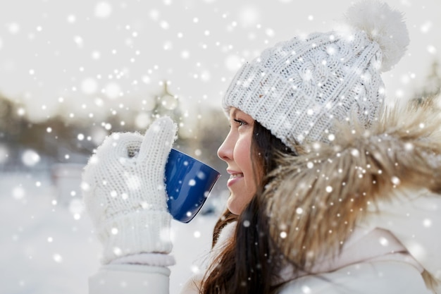 gente, temporada, bebidas y concepto de ocio - mujer joven feliz con taza de té al aire libre en invierno