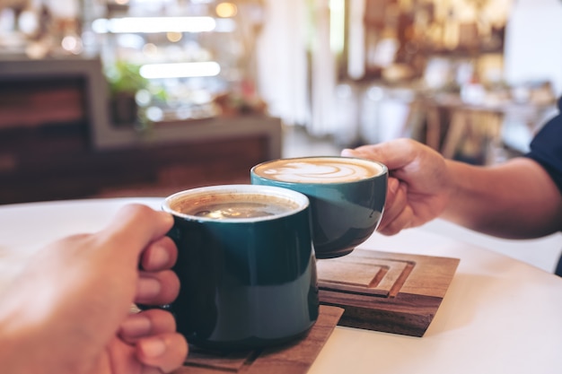 Gente tintineo de tazas de café en la cafetería