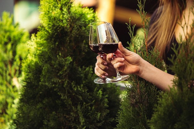 Gente tintineo de vasos con vino en la terraza de verano de cafetería o restaurante.