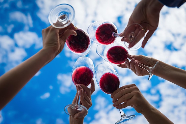 Gente tintineo de vasos con vino en la terraza de verano de cafetería o restaurante