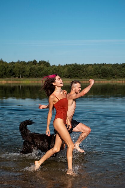 Gente de tiro completo jugando con perro en la playa