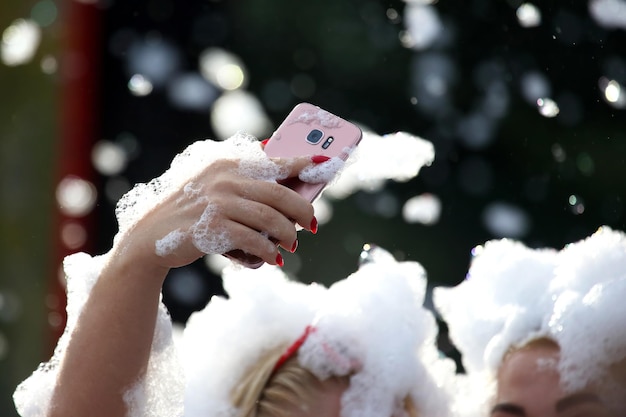 La gente se toma un selfie con un teléfono móvil en espuma jabonosa en un concierto.