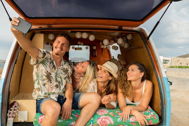 Gente tomando selfie dentro de una autocaravana en la playa