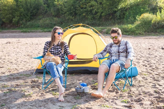 Gente, turismo de verano y concepto de naturaleza - pareja joven bebiendo té cerca de la tienda.