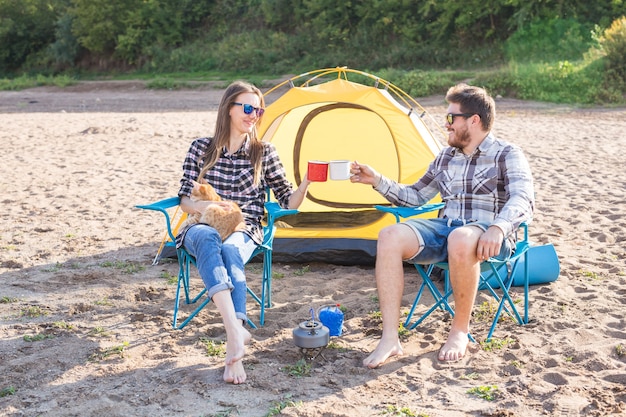 Gente, turismo de verano y concepto de naturaleza - pareja joven bebiendo té cerca de la tienda.